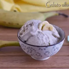 Una ciotola di cremoso gelato alla banana, guarnito con fettine di banana, accanto a banane fresche e un cucchiaino.