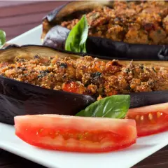 Melanzane ripiene al forno velocissime, dorate e gustose, servite con pomodoro fresco e basilico.