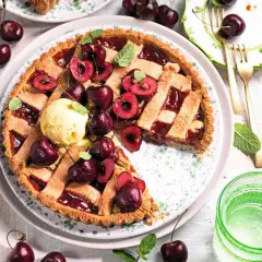 Una deliziosa crostata di ciliegie, guarnita con ciliegie fresche, gelato alla vaniglia e foglioline di menta. Perfetta per un dolce estivo.