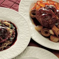 Stinco di maiale in pentola, tenero e succulento, servito con verdure e una ricca salsa.