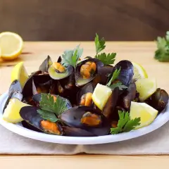 Un piatto fumante di impepata di cozze, guarnito con limone fresco e prezzemolo, pronto per essere gustato.
