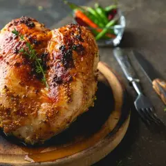 Succulento petto di pollo al forno, dorato e speziato, pronto per essere gustato con erbe aromatiche e peperoncini.