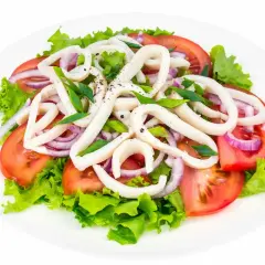Deliziosa insalata di calamari con pomodori, cipolla rossa e lattuga fresca, condita con erbe aromatiche.