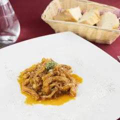 Un piatto di trippa alla fiorentina, saporita e profumata, servita su un piatto bianco con una spolverata di parmigiano.