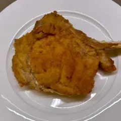 Cotoletta alla valdostana dorata e croccante su piatto bianco, pronta per essere gustata.