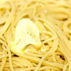 Un piatto di pasta in bianco, con spaghetti conditi da una generosa porzione di burro che si scioglie.