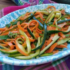 Deliziosa insalata di zucchine e carote a julienne, guarnita con menta fresca. Un piatto leggero e colorato.