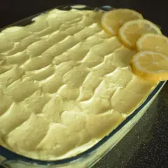 Tiramisù al limone pronto per essere gustato, decorato con fette di limone fresco e limoni interi.