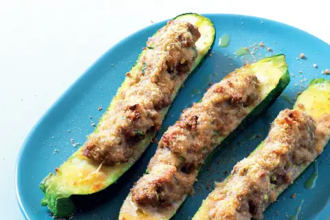 Zucchine ripiene velocissime, dorate e croccanti, servite su un piatto blu. Un piatto semplice e gustoso.