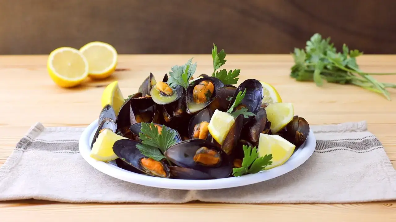 Un piatto fumante di impepata di cozze, guarnito con limone fresco e prezzemolo, pronto per essere gustato.