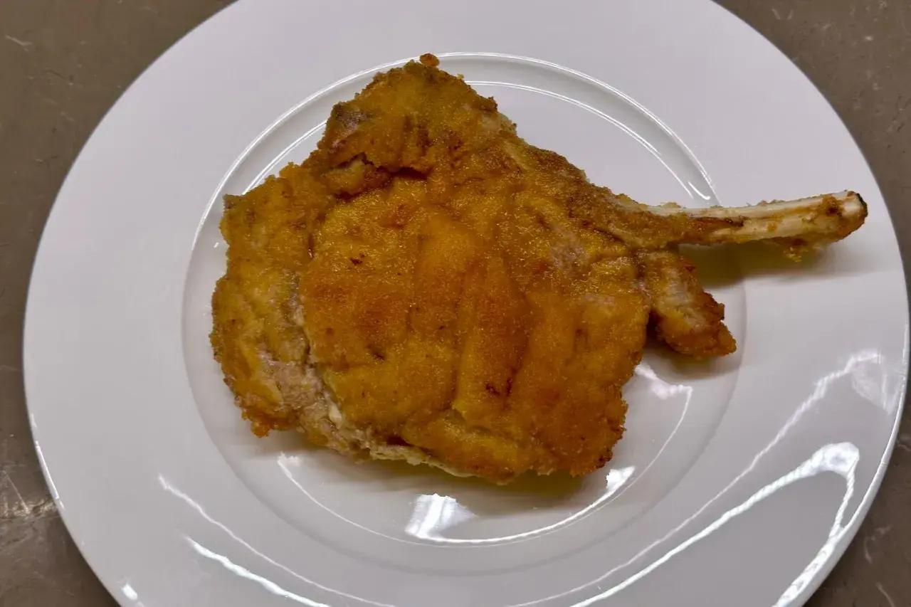 Cotoletta alla valdostana dorata e croccante su piatto bianco, pronta per essere gustata.