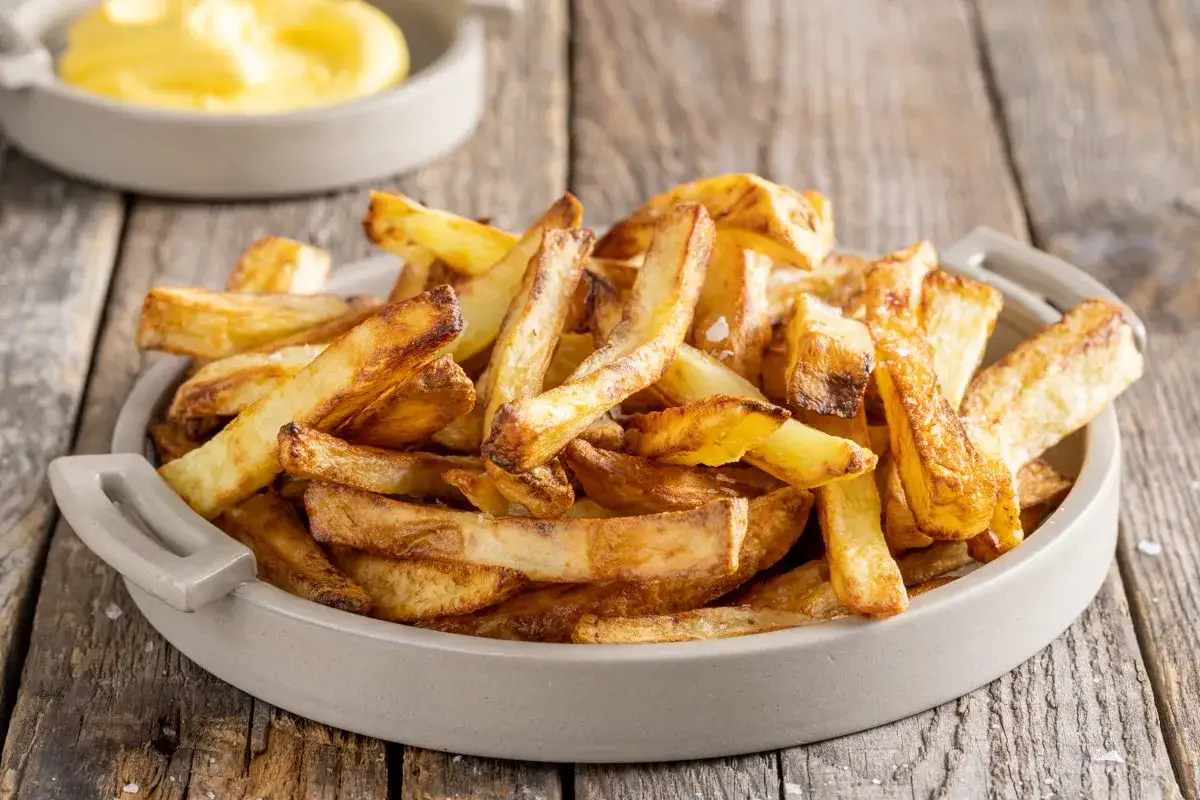 Patate croccanti in friggitrice ad aria, dorate e salate, pronte per essere gustate.