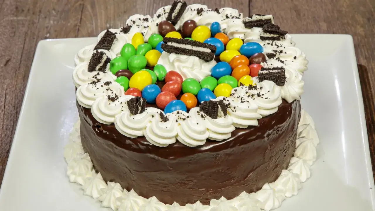 Torta al cioccolato con panna, caramelle colorate e biscotti Oreo, perfetta tra le torte di compleanno semplici da fare in casa.