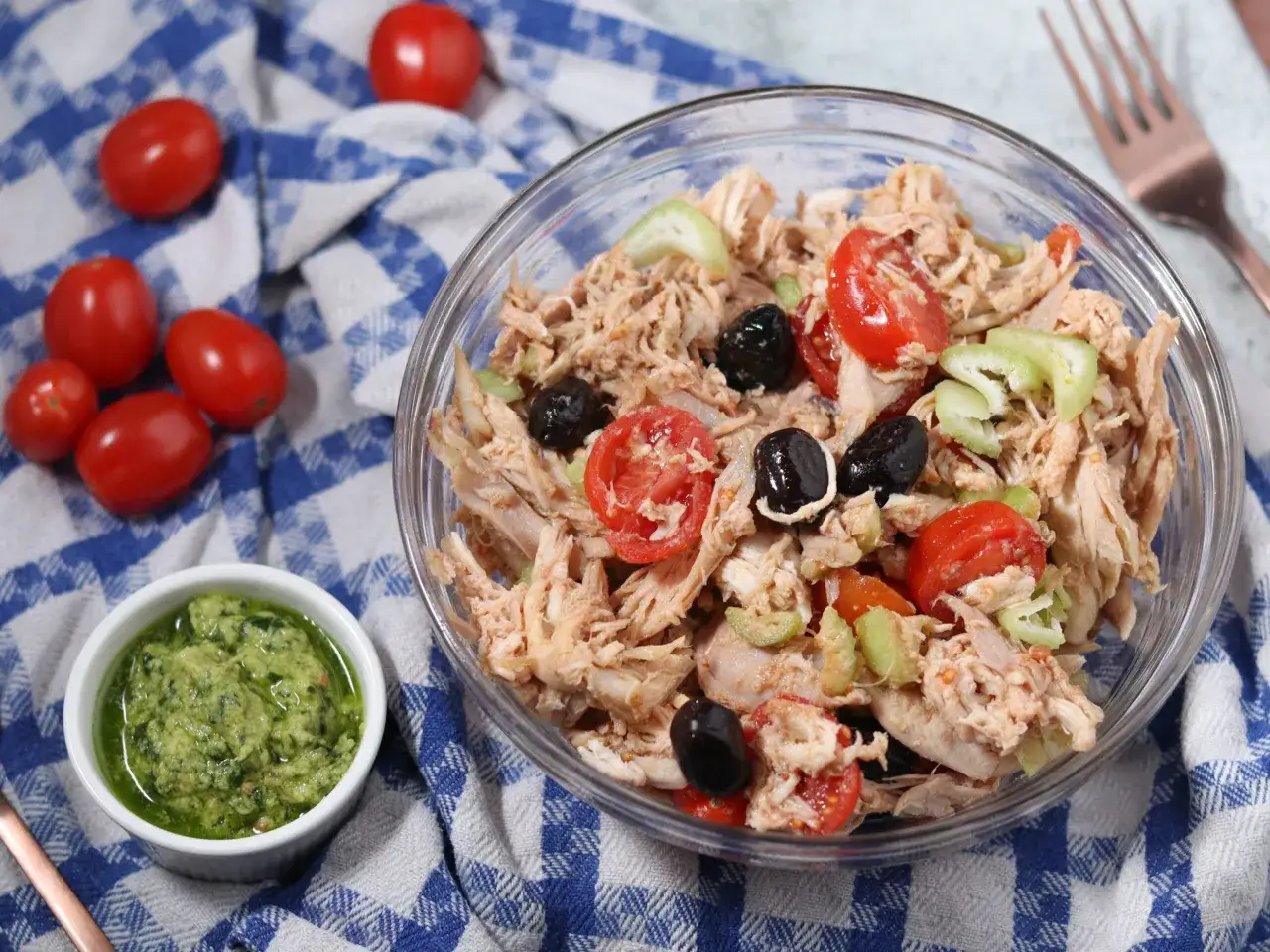 Insalata di pollo sfiziosa con pomodorini, olive nere e sedano. Accanto, una ciotolina di salsa verde.