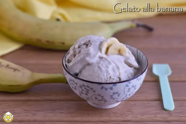 Una ciotola di cremoso gelato alla banana, guarnito con fettine di banana, accanto a banane fresche e un cucchiaino.