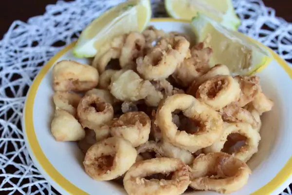 Un piatto invitante di frittura di calamari dorati e croccanti, accompagnati da spicchi di limone fresco.